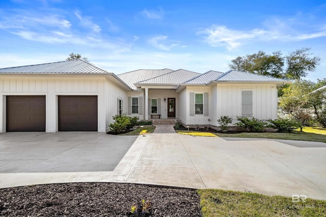 modern farmhouse style home featuring board and batten siding, concrete driveway, metal roof, and a garage