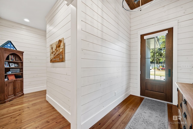 entrance foyer featuring light wood-style floors, recessed lighting, wooden walls, and baseboards