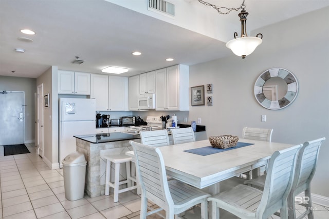 kitchen featuring light tile patterned flooring, white appliances, visible vents, white cabinets, and pendant lighting