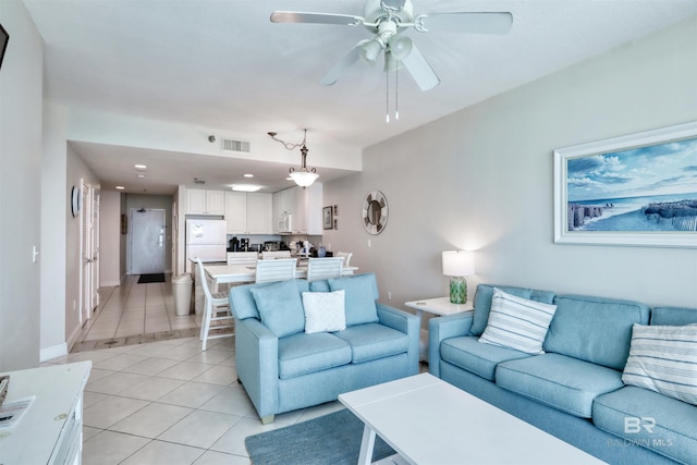 living room featuring light tile patterned floors, ceiling fan, visible vents, and baseboards