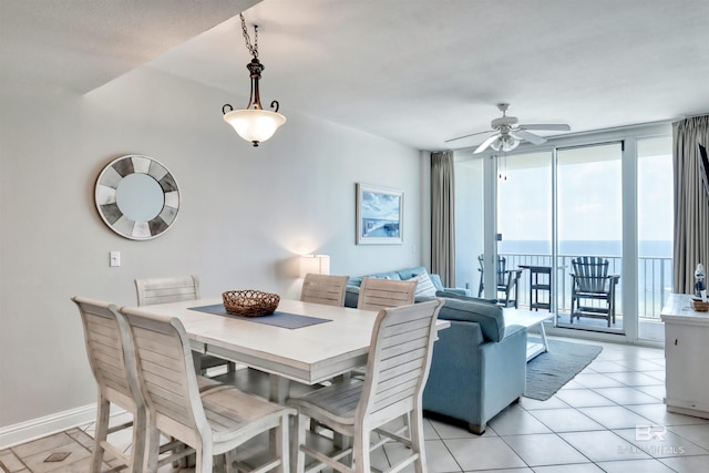 dining space with light tile patterned floors, ceiling fan, baseboards, and a wall of windows