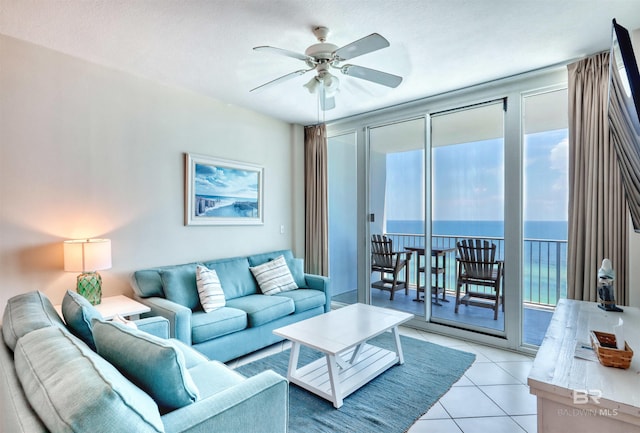 living area featuring a water view, light tile patterned floors, and ceiling fan