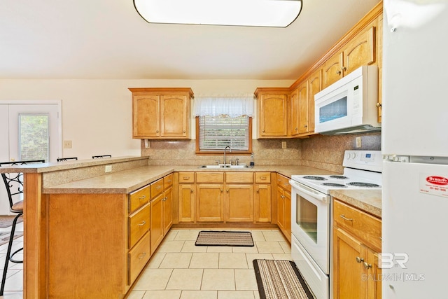 kitchen featuring light tile patterned flooring, white appliances, sink, a breakfast bar, and kitchen peninsula