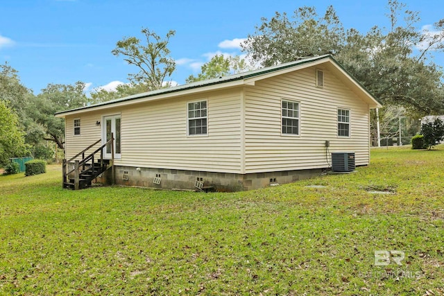 back of property with central AC and a lawn