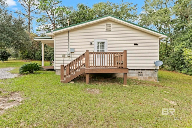 rear view of property featuring a wooden deck and a lawn