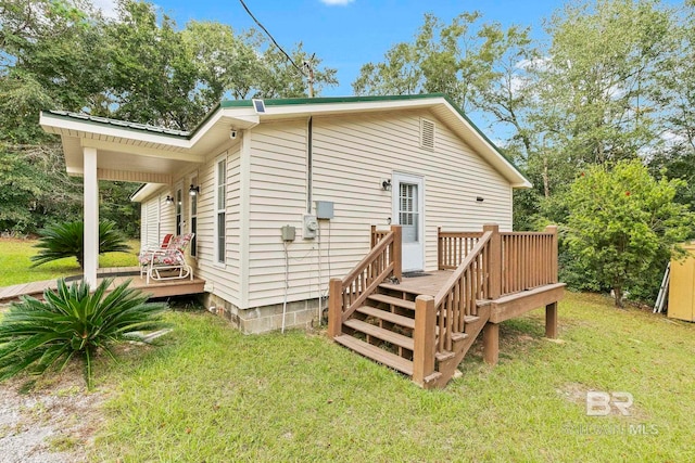 back of property featuring a deck and a yard