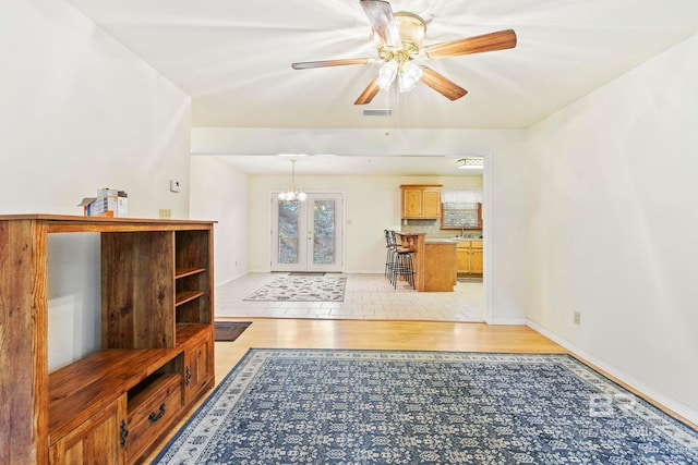 unfurnished living room featuring sink, ceiling fan, french doors, and light hardwood / wood-style floors