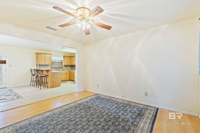 unfurnished living room with light hardwood / wood-style floors, ceiling fan, and sink