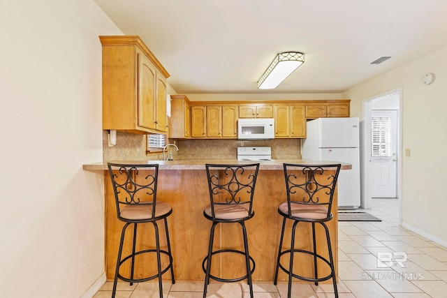 kitchen with kitchen peninsula, sink, tasteful backsplash, a breakfast bar, and white appliances