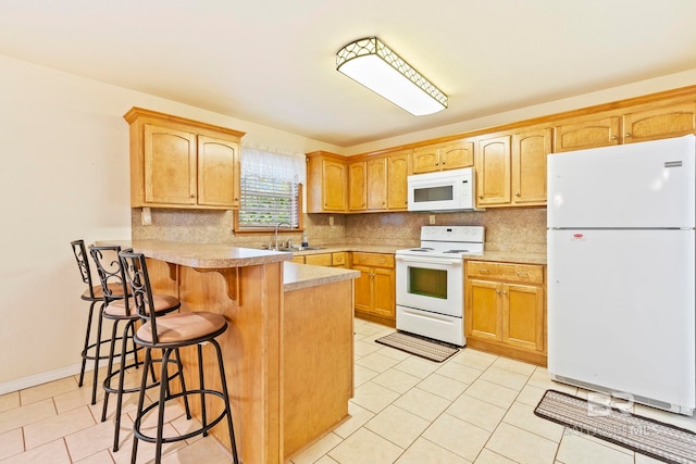 kitchen with tasteful backsplash, white appliances, sink, a kitchen breakfast bar, and kitchen peninsula