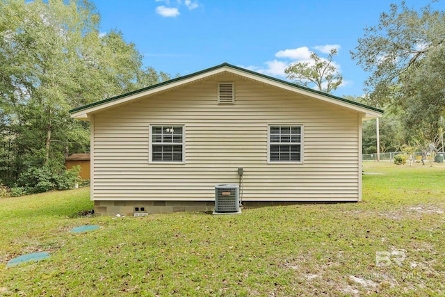 view of side of property with central AC unit and a yard