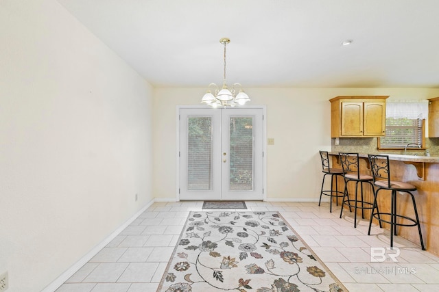 tiled dining space with sink, french doors, and a notable chandelier