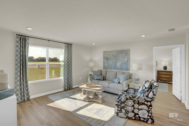 living area featuring baseboards, visible vents, wood finished floors, and recessed lighting