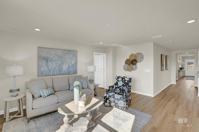 living room featuring baseboards, light wood-style flooring, and recessed lighting