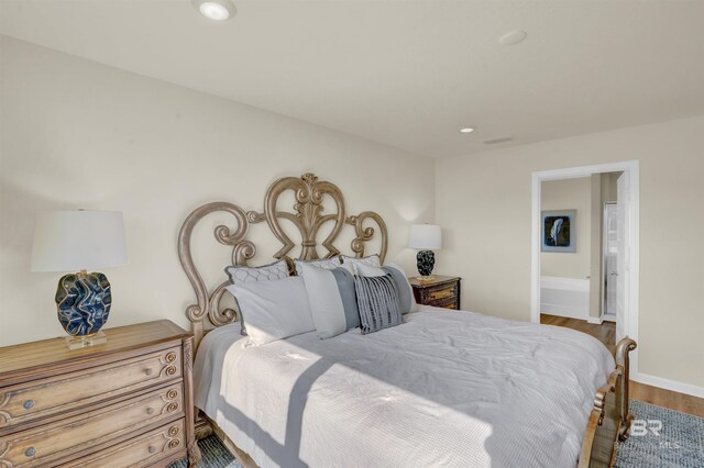 bedroom featuring visible vents, baseboards, connected bathroom, wood finished floors, and recessed lighting
