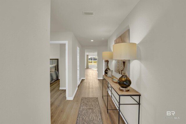 hallway with baseboards, light wood-type flooring, visible vents, and recessed lighting
