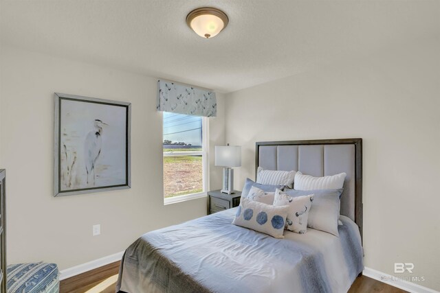 bedroom with baseboards and wood finished floors
