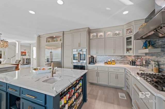 30471 Harbour Dr, Orange Beach, AL 36561 - kitchen with blue cabinetry, decorative columns, range hood, appliances with stainless steel finishes, and open shelves