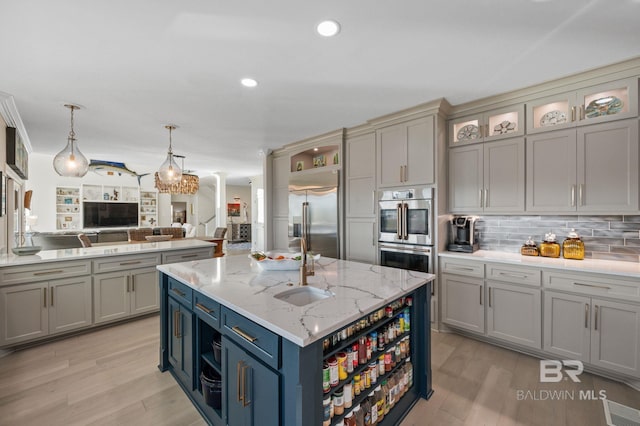30471 Harbour Dr, Orange Beach, AL 36561 - kitchen with light wood-type flooring, a center island with sink, tasteful backsplash, stainless steel appliances, and decorative columns
