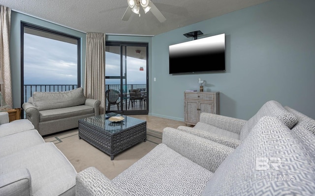 living area with a textured ceiling, ceiling fan, tile patterned floors, and baseboards