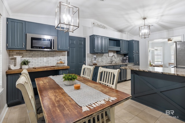 kitchen with blue cabinetry, appliances with stainless steel finishes, sink, and vaulted ceiling