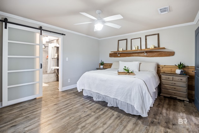 bedroom featuring crown molding, a barn door, dark hardwood / wood-style flooring, ceiling fan, and ensuite bathroom