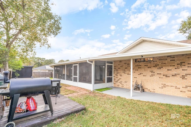 rear view of property featuring a sunroom, a yard, and a deck