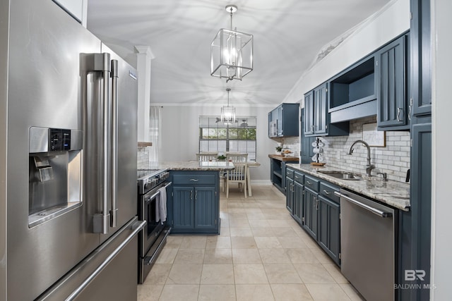 kitchen featuring high end appliances, sink, blue cabinetry, light tile patterned flooring, and decorative light fixtures