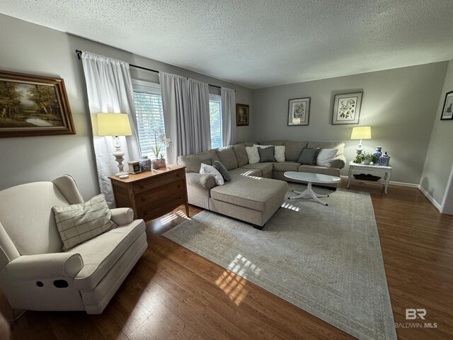 living area with dark wood-style floors, baseboards, and a textured ceiling