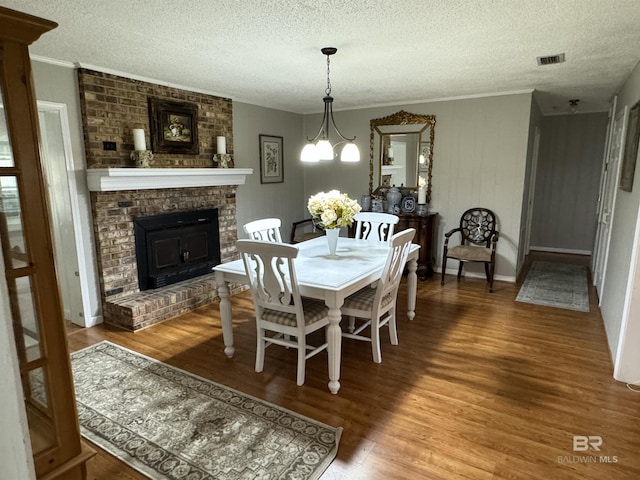 dining area featuring visible vents, a fireplace, a textured ceiling, and wood finished floors