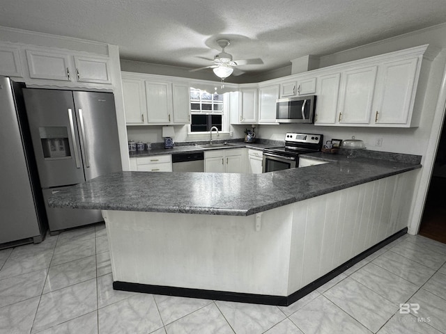 kitchen featuring a peninsula, white cabinetry, appliances with stainless steel finishes, and a sink