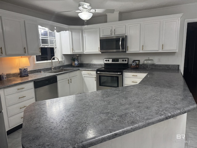 kitchen featuring dark countertops, appliances with stainless steel finishes, white cabinets, and a sink