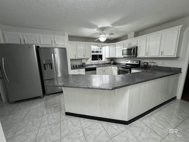 kitchen featuring a peninsula, a sink, white cabinetry, a ceiling fan, and appliances with stainless steel finishes