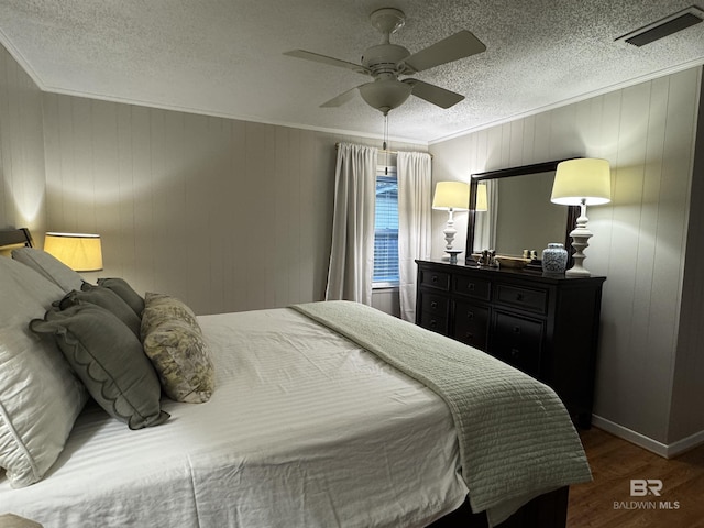 bedroom with visible vents, ornamental molding, ceiling fan, a textured ceiling, and wood finished floors