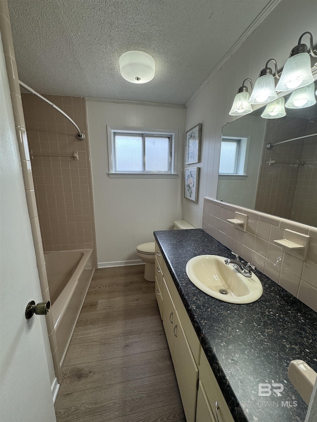 full bathroom with backsplash, toilet, vanity, a textured ceiling, and wood finished floors