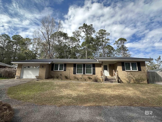 ranch-style house featuring a garage, metal roof, aphalt driveway, and brick siding