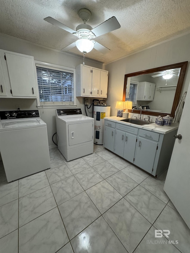 clothes washing area featuring cabinet space, electric water heater, washing machine and clothes dryer, crown molding, and a sink