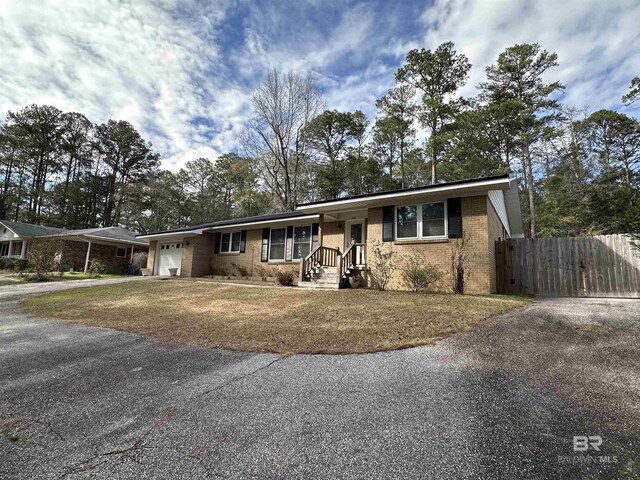 ranch-style home with an attached garage, driveway, fence, and brick siding
