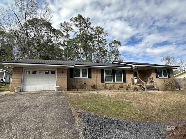 ranch-style house featuring aphalt driveway, brick siding, metal roof, and an attached garage