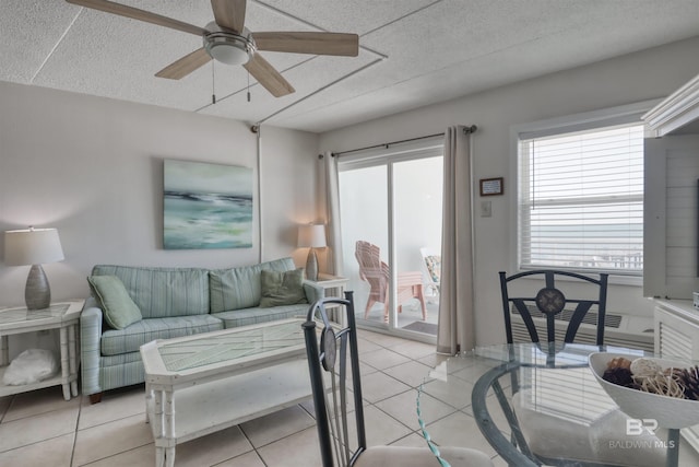 living area with light tile patterned floors, plenty of natural light, and a ceiling fan