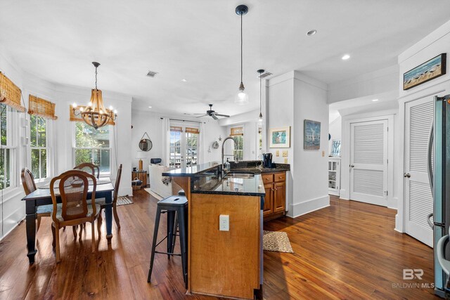 25773 Canal Rd Unit 28, Orange Beach, AL 36561 - kitchen with visible vents, decorative light fixtures, a kitchen breakfast bar, dark wood-style floors, and brown cabinetry