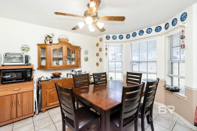 tiled dining space with ceiling fan and a textured ceiling