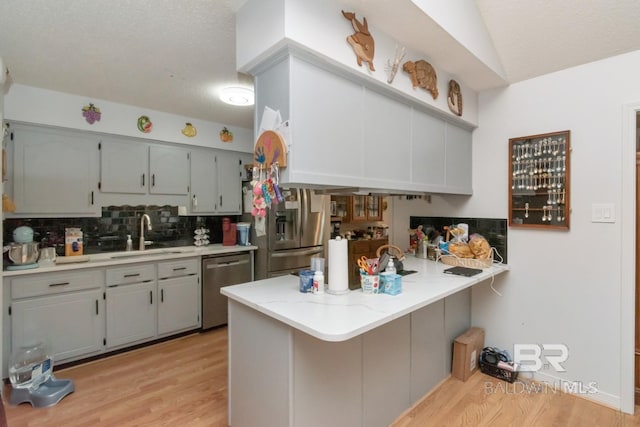 kitchen featuring sink, backsplash, stainless steel appliances, a kitchen breakfast bar, and kitchen peninsula