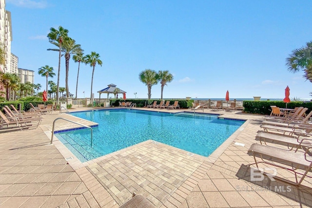 community pool with fence, a gazebo, and a patio area