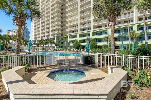 pool with fence and a hot tub