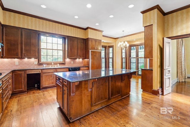 kitchen featuring light hardwood / wood-style flooring, plenty of natural light, dark stone counters, and a center island