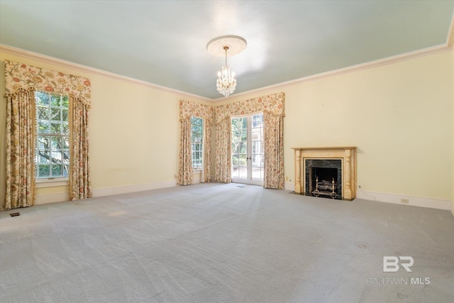 unfurnished living room with crown molding, a fireplace, a chandelier, and carpet