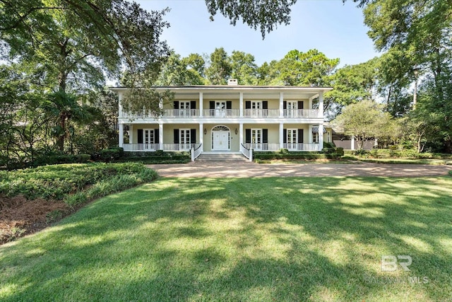 neoclassical home with a front yard, a balcony, and covered porch