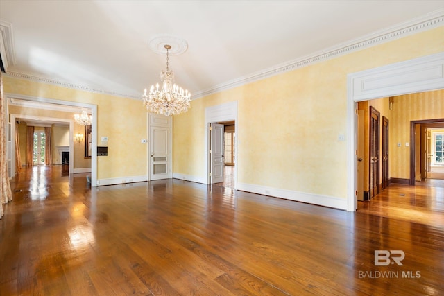 spare room featuring wood-type flooring, a notable chandelier, and crown molding