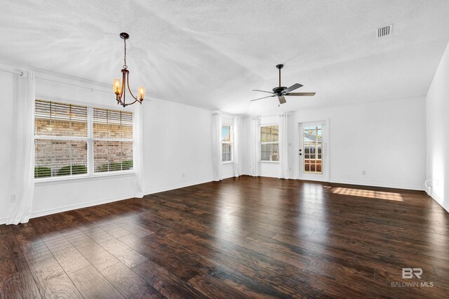 unfurnished living room featuring wood finished floors, visible vents, baseboards, and ceiling fan with notable chandelier